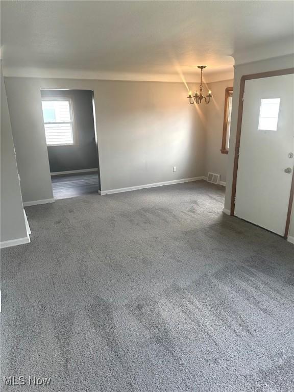 carpeted spare room with a notable chandelier