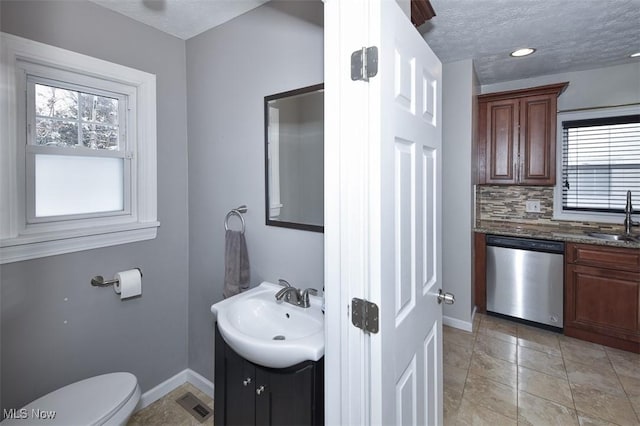 bathroom with vanity, tasteful backsplash, toilet, and a textured ceiling