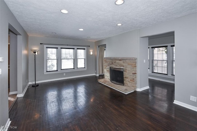 unfurnished living room with dark wood-type flooring, a textured ceiling, and a fireplace