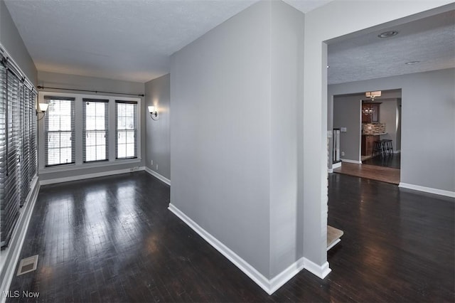 spare room featuring a textured ceiling and dark hardwood / wood-style flooring