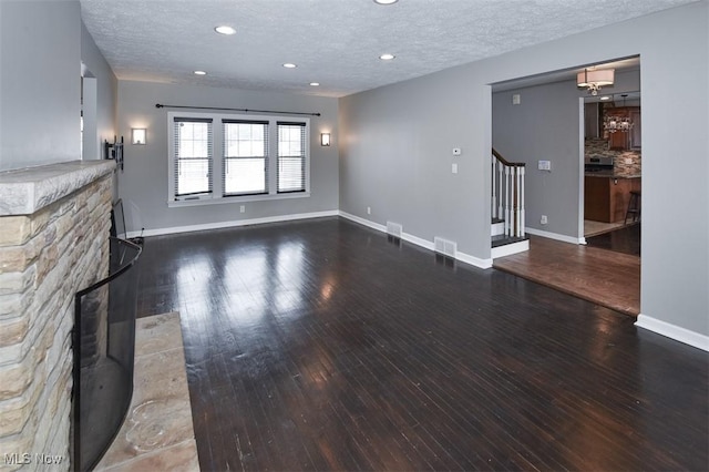 unfurnished living room with dark wood-type flooring and a textured ceiling