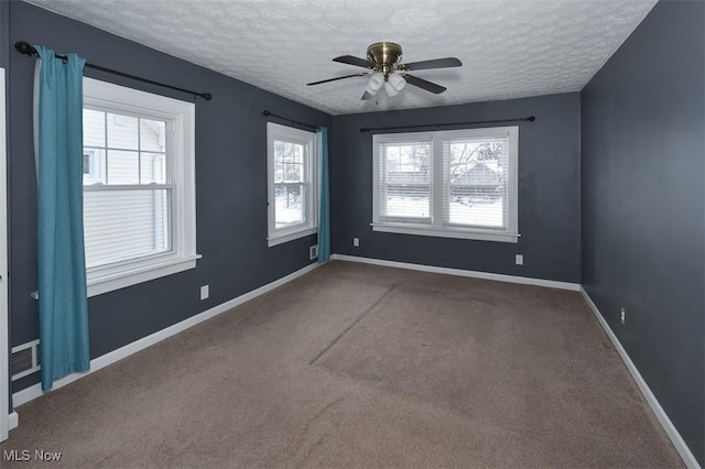 carpeted spare room with a textured ceiling and ceiling fan