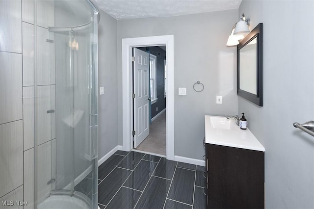 bathroom with a textured ceiling, an enclosed shower, and vanity