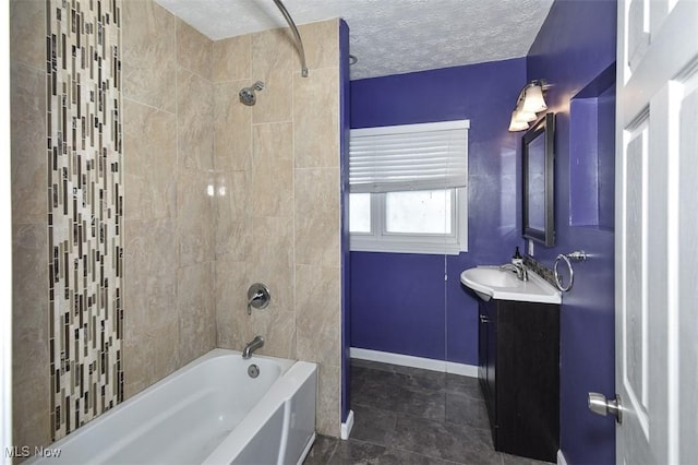 bathroom with a textured ceiling, vanity, and tiled shower / bath combo