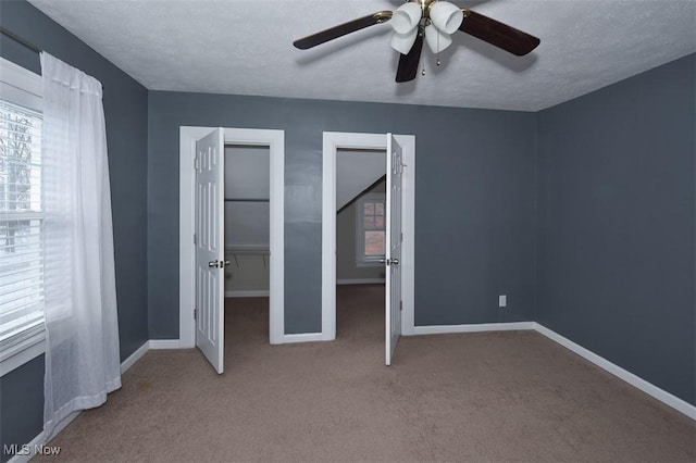 unfurnished bedroom featuring ceiling fan, carpet floors, and a textured ceiling