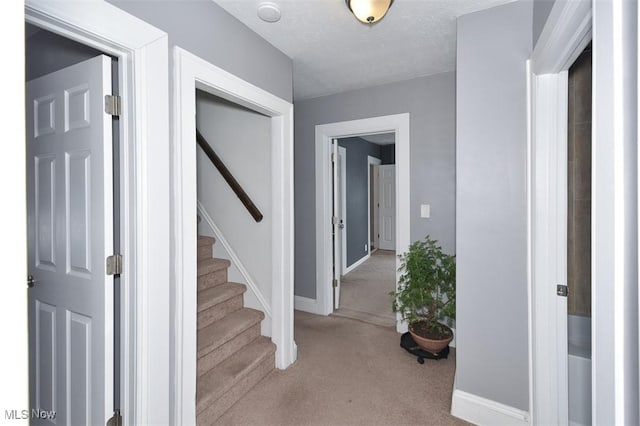 hallway with a textured ceiling and light colored carpet