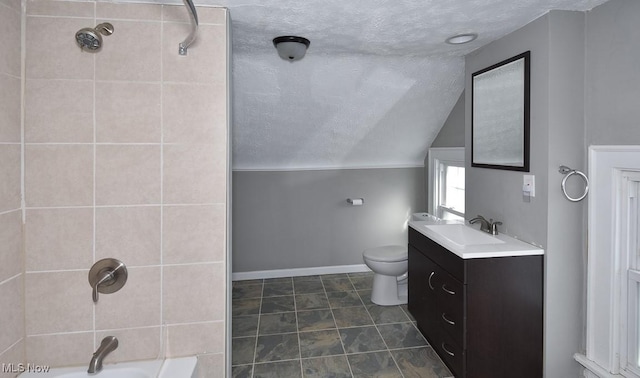 full bathroom with vaulted ceiling, vanity, a textured ceiling, tiled shower / bath combo, and toilet