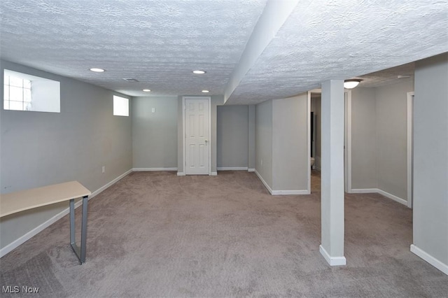 basement with a textured ceiling and light colored carpet