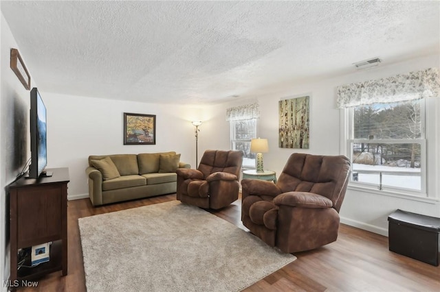 living room featuring dark hardwood / wood-style flooring, a textured ceiling, and a wealth of natural light