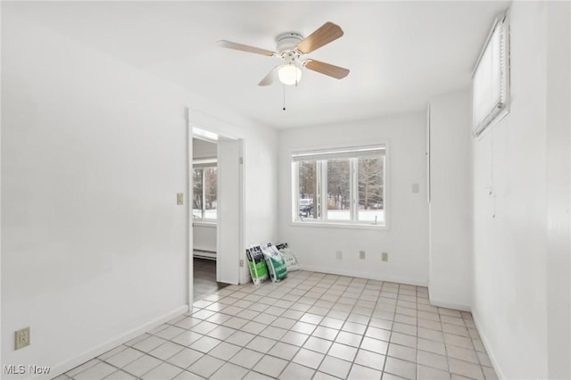 unfurnished bedroom featuring ceiling fan, light tile patterned floors, and a baseboard heating unit