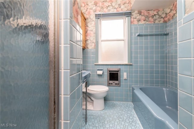 bathroom with heating unit, tile patterned flooring, plus walk in shower, toilet, and tile walls