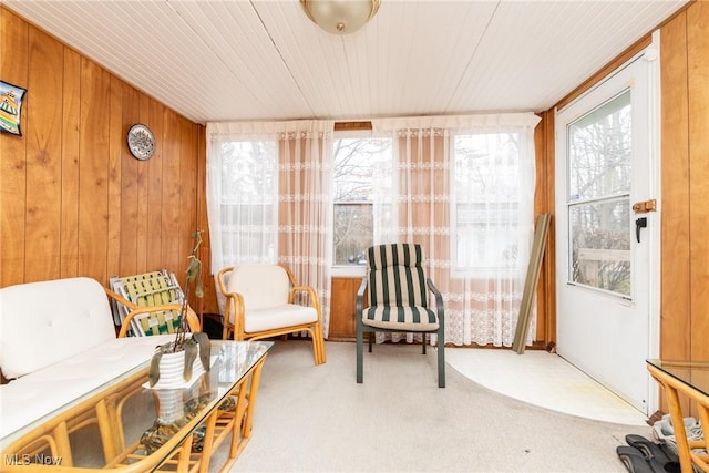 sitting room featuring wooden walls, wooden ceiling, and light colored carpet