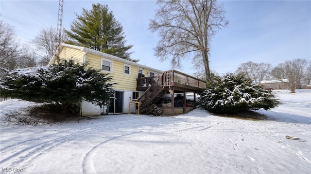 snow covered rear of property with a wooden deck