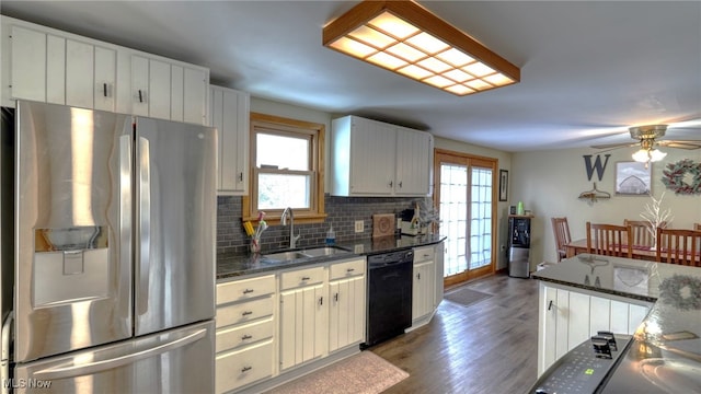 kitchen featuring dark stone countertops, sink, black dishwasher, stainless steel refrigerator with ice dispenser, and backsplash