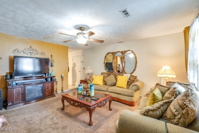 carpeted living room featuring ceiling fan and a textured ceiling