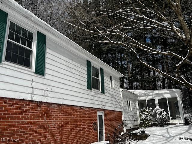 snow covered property with a sunroom