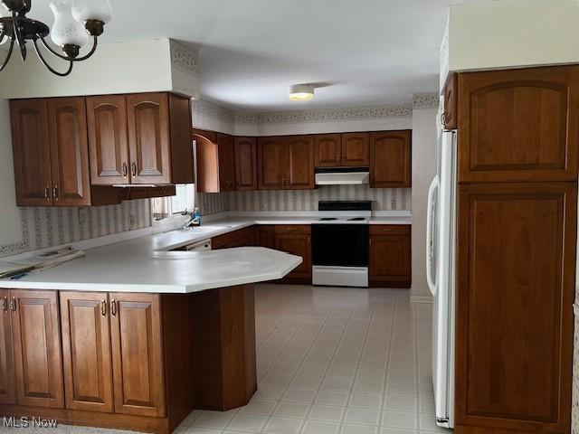 kitchen with white appliances, a chandelier, sink, and kitchen peninsula