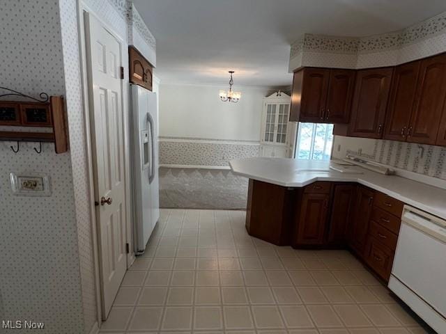 kitchen with kitchen peninsula, hanging light fixtures, white appliances, dark brown cabinets, and a chandelier