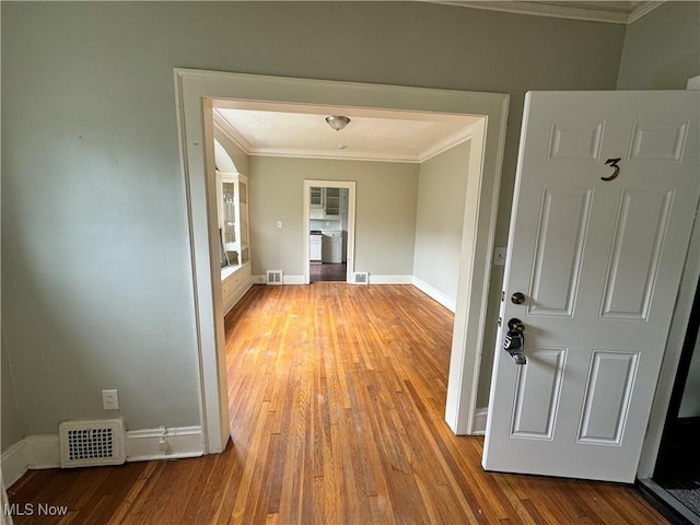 empty room with hardwood / wood-style flooring and crown molding