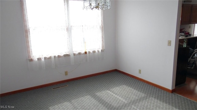 empty room with carpet floors and an inviting chandelier