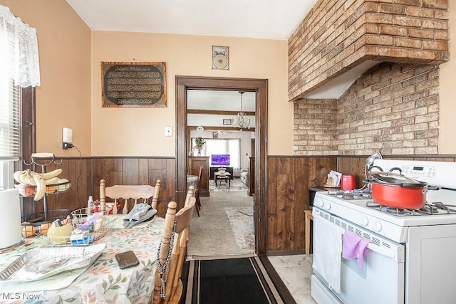 kitchen featuring wooden walls and white range with gas cooktop