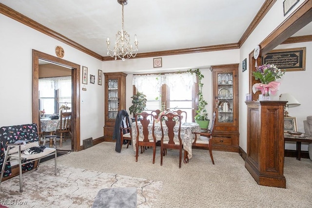 carpeted dining room with a healthy amount of sunlight, a chandelier, and crown molding