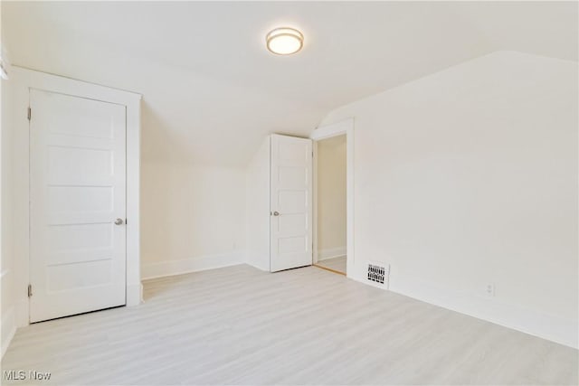 unfurnished room featuring lofted ceiling and light hardwood / wood-style flooring