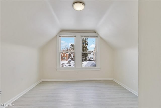 additional living space with vaulted ceiling and light hardwood / wood-style flooring