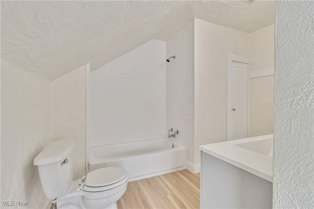 full bathroom with a textured ceiling, wood-type flooring, toilet, and tub / shower combination