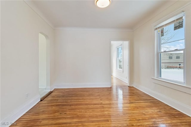 empty room with light wood-type flooring and crown molding