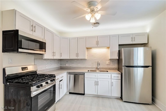 kitchen featuring light hardwood / wood-style floors, sink, tasteful backsplash, ceiling fan, and appliances with stainless steel finishes