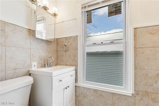 bathroom with tile walls, vanity, and toilet