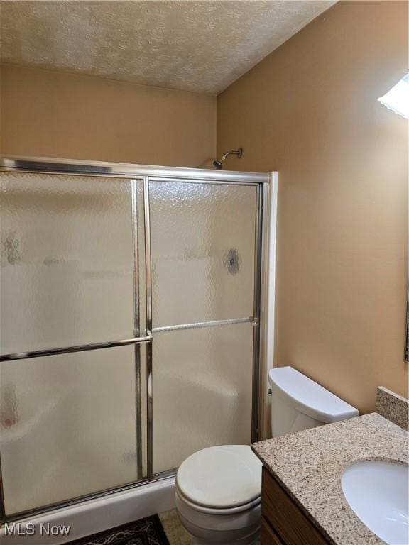 bathroom with a shower with shower door, toilet, a textured ceiling, and vanity