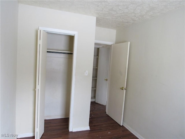 unfurnished bedroom featuring dark hardwood / wood-style flooring, a textured ceiling, and a closet