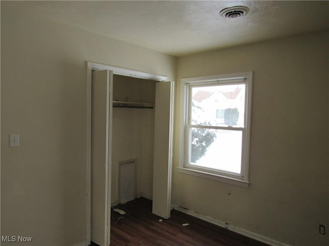 unfurnished bedroom with dark wood-type flooring and a closet