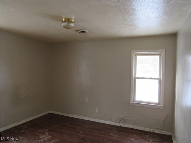 spare room with dark hardwood / wood-style flooring and a textured ceiling