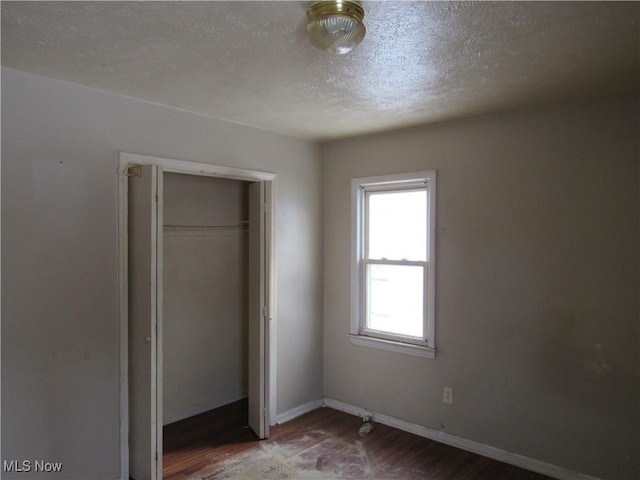 unfurnished bedroom featuring a textured ceiling, a closet, and hardwood / wood-style floors