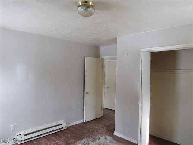 unfurnished bedroom with a baseboard heating unit, a closet, a textured ceiling, and dark hardwood / wood-style flooring