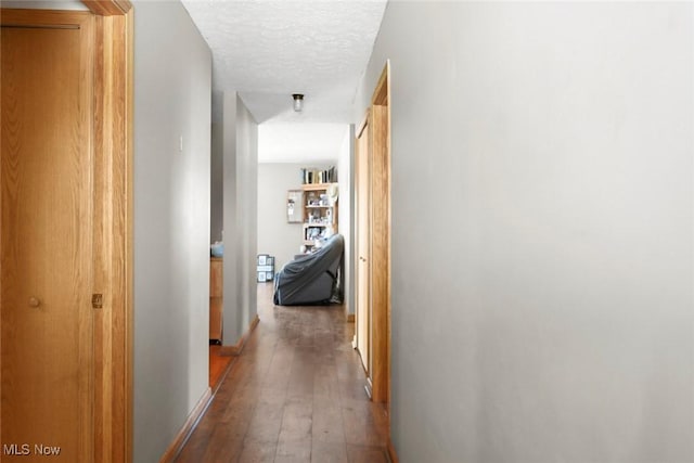 hallway with hardwood / wood-style floors and a textured ceiling