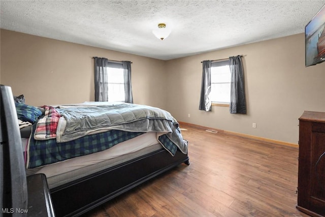 bedroom featuring multiple windows, hardwood / wood-style floors, and a textured ceiling