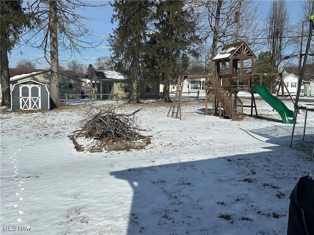 yard covered in snow featuring a storage unit and a playground