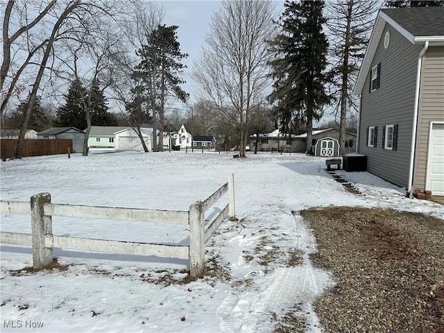 snowy yard featuring a storage unit