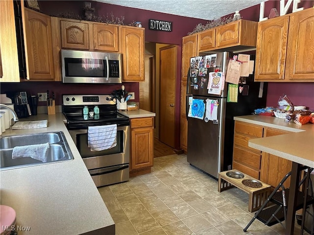 kitchen with appliances with stainless steel finishes, sink, and a textured ceiling