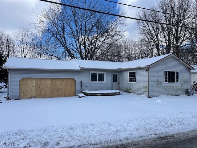 snow covered back of property featuring a garage