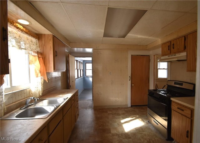 kitchen featuring stainless steel gas stove, sink, and backsplash