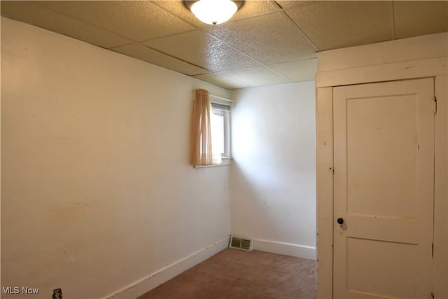 carpeted empty room featuring a drop ceiling