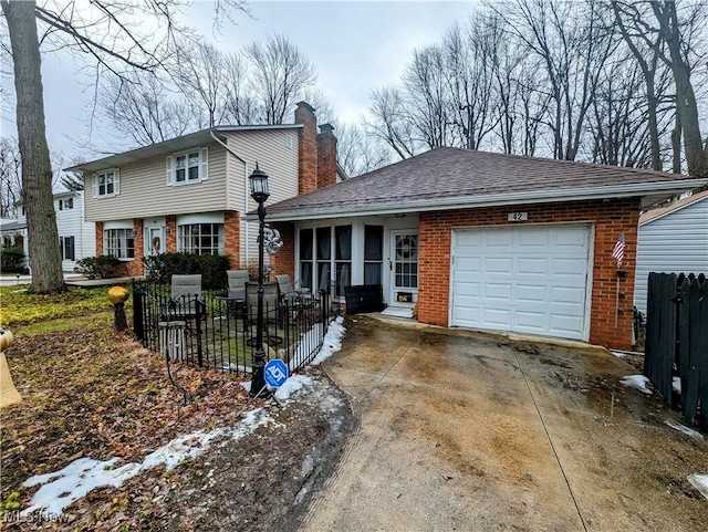 view of front of house with an attached garage, driveway, fence, and brick siding