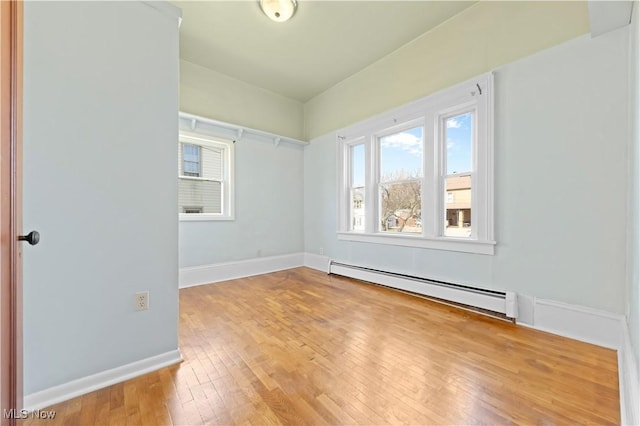 spare room with a baseboard radiator, baseboards, and hardwood / wood-style flooring