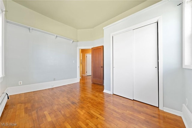 unfurnished bedroom featuring hardwood / wood-style floors, a closet, and baseboards
