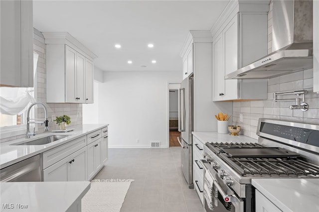 kitchen featuring sink, appliances with stainless steel finishes, white cabinets, and wall chimney exhaust hood